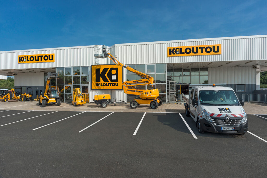 Façade d'une agence Kiloutou avec du matériel de location et un véhicule utilitaire